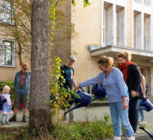 Eine Gruppe Menschen gießt einen Baum
